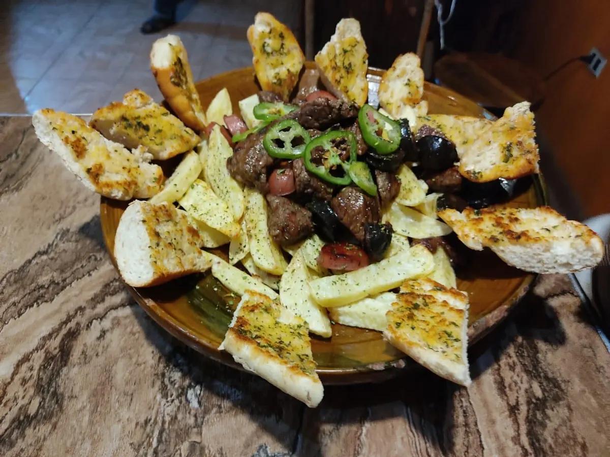 Plato de carne con papas, pan y ají
